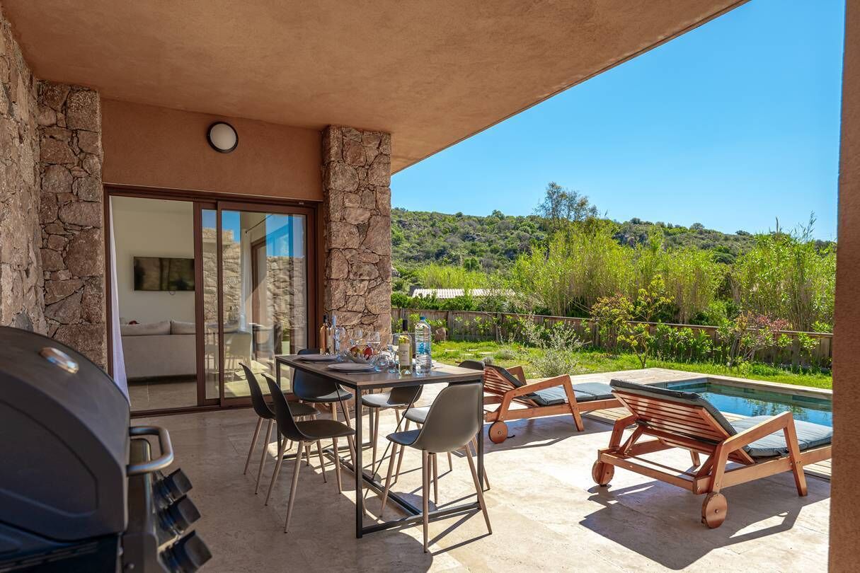 Une terrasse avec un barbecue, une table à manger, des chaises et un espace piscine.