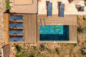 An aerial view of a pool area with wooden deck, lounge chairs, and a swimming pool. - Superb new stone villa SEA VIEW Palombaggia (PORTO VECCHIO)