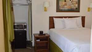 A hotel room with a bed, a nightstand, a microwave, and a painting on the wall. - #16 FAMILY SUITE , 3 BEDS with WiFi, and AC in Columbia Falls, 20 mi to GNP (Columbia Falls)