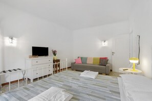 Ett sovrum med en säng, en tv, en soffa, ett skrivbord och en lampa.