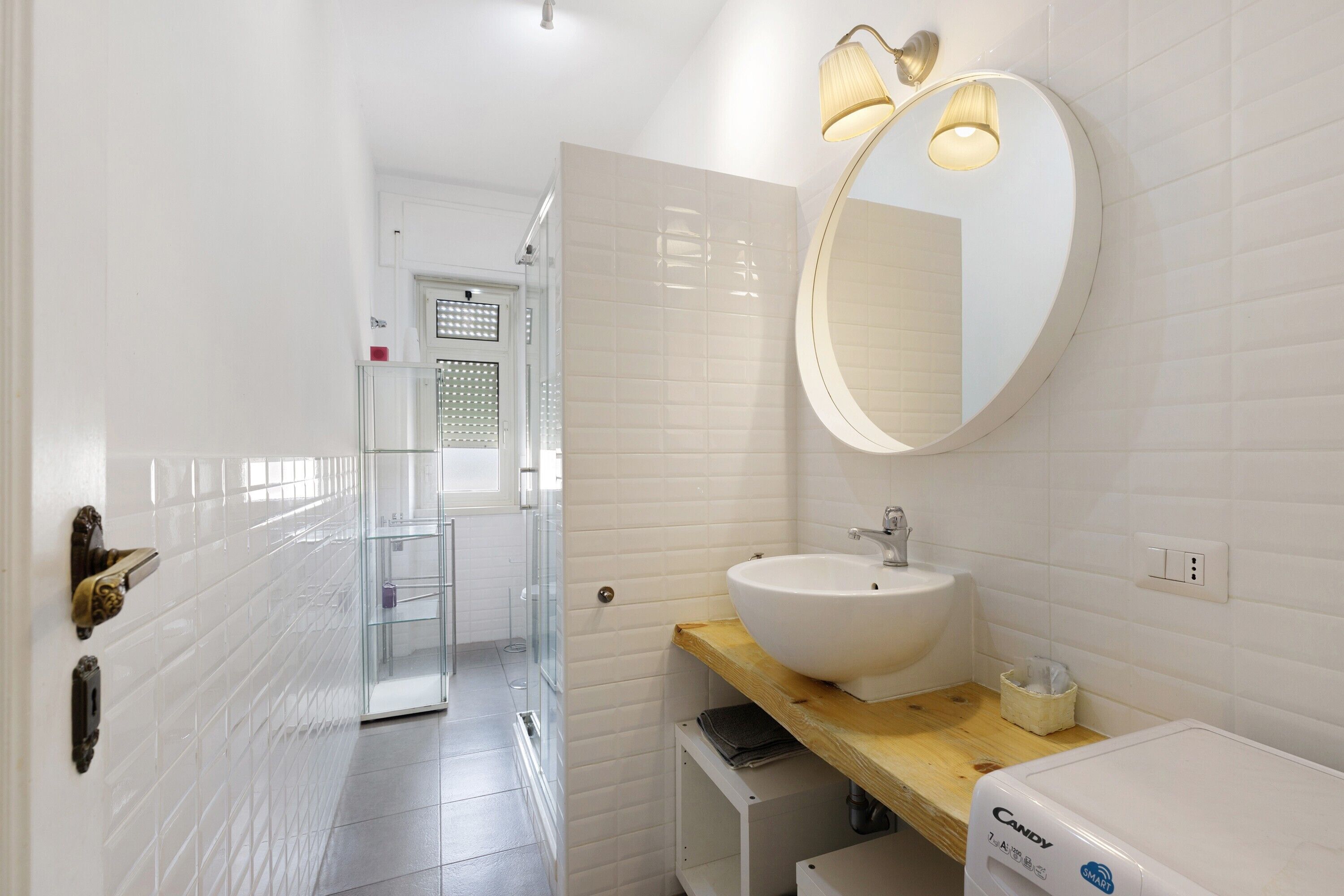 Un bagno con un lavandino bianco, uno specchio e un porta asciugamani.