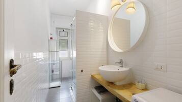 Un bagno con un lavandino bianco, uno specchio e un porta asciugamani.