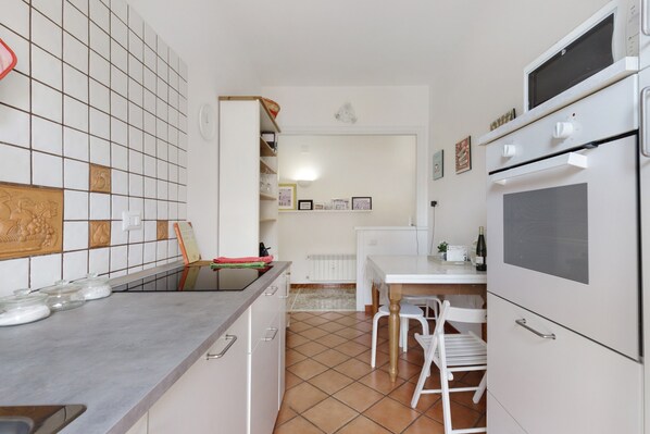 A kitchen with a tiled backsplash, a countertop with glass jars, a dining table with chairs, and a built-in oven.