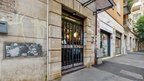 A building with a storefront, a metal gate, and a sign for 'Vera Estetica Salon.' - Apartment 'Amy Home' with Balcony, Wi-Fi and Air Conditioning (Roma)