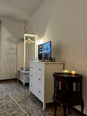 Une chambre avec un lit, une commode, une télévision et une petite table avec des bougies.