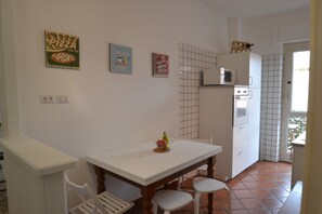 Une cuisine avec une table blanche, des chaises, un four à micro-ondes et une enseigne publicitaire pour une pizzeria accrochée au mur.