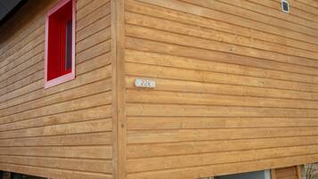 Une cabane en bois avec une fenêtre rouge et une plaque portant un numéro.