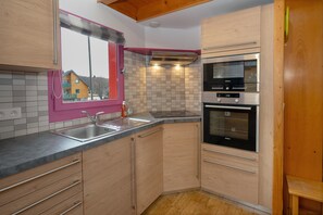 A kitchen with a stainless steel sink, a microwave, and an oven. - Chalet '228 - Village Nordique' with Mountain View, Shared Pool and Private Terrace (Les Deserts)