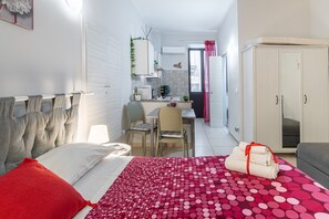 A bedroom with a bed, a desk, a chair, and a wardrobe. - Apartment 'La Fonte Di Ortigia - Casa Alfeo' with Balcony, Wi-Fi and Air Conditioning (Siracusa)