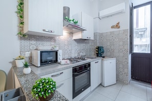 Una cucina compatta con forno a microonde, fornelli, forno e un piccolo frigorifero.