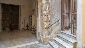 A stone building with a metal gate, a bicycle, and a staircase.