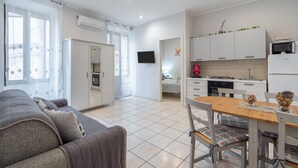 A modern apartment with a living room, dining area, kitchenette, and a bedroom.