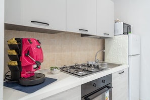 A kitchen with a gas stove, a coffee machine, a refrigerator, and a microwave. - Apartment 'La Fonte Di Ortigia - Casa Aretusa' with Balcony, Wi-Fi and Air Conditioning (Siracusa)