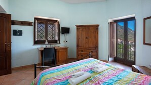 Une chambre à coucher comprenant un lit, un bureau, une armoire, une fenêtre et un balcon.