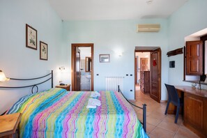 A bedroom with a bed, bedside tables, a desk, and a chair. There are doors leading to other rooms.