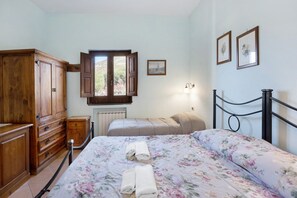 A bedroom with a bed, a wooden wardrobe, a window, and a wall-mounted light fixture. - Room 'Pompei Con Vista Montagna' with Shared Terrace, Shared Garden and Wi-Fi (Castello)