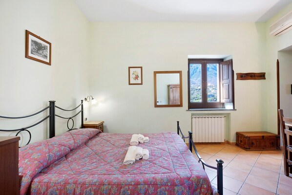 A bedroom with a bed, a window, a radiator, and a wooden chest.