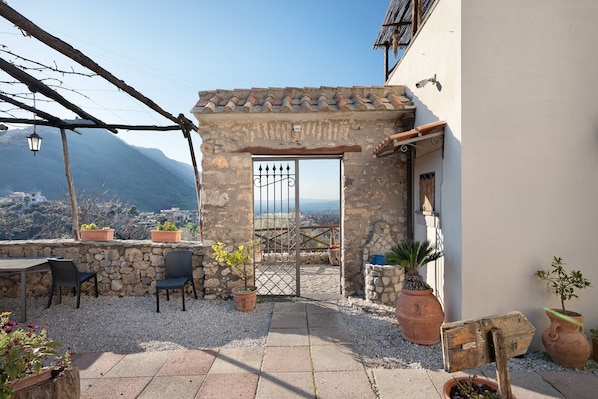 A stone patio with chairs, potted plants, and a view of the mountains.