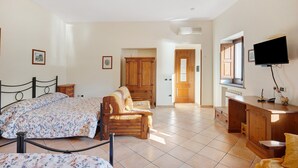 A bedroom with a bed, a wooden chair, a desk, and a television. - Room 'Capri Con Vista Monti E Cortile' with Shared Terrace, Shared Garden and Wi-Fi (Castello)