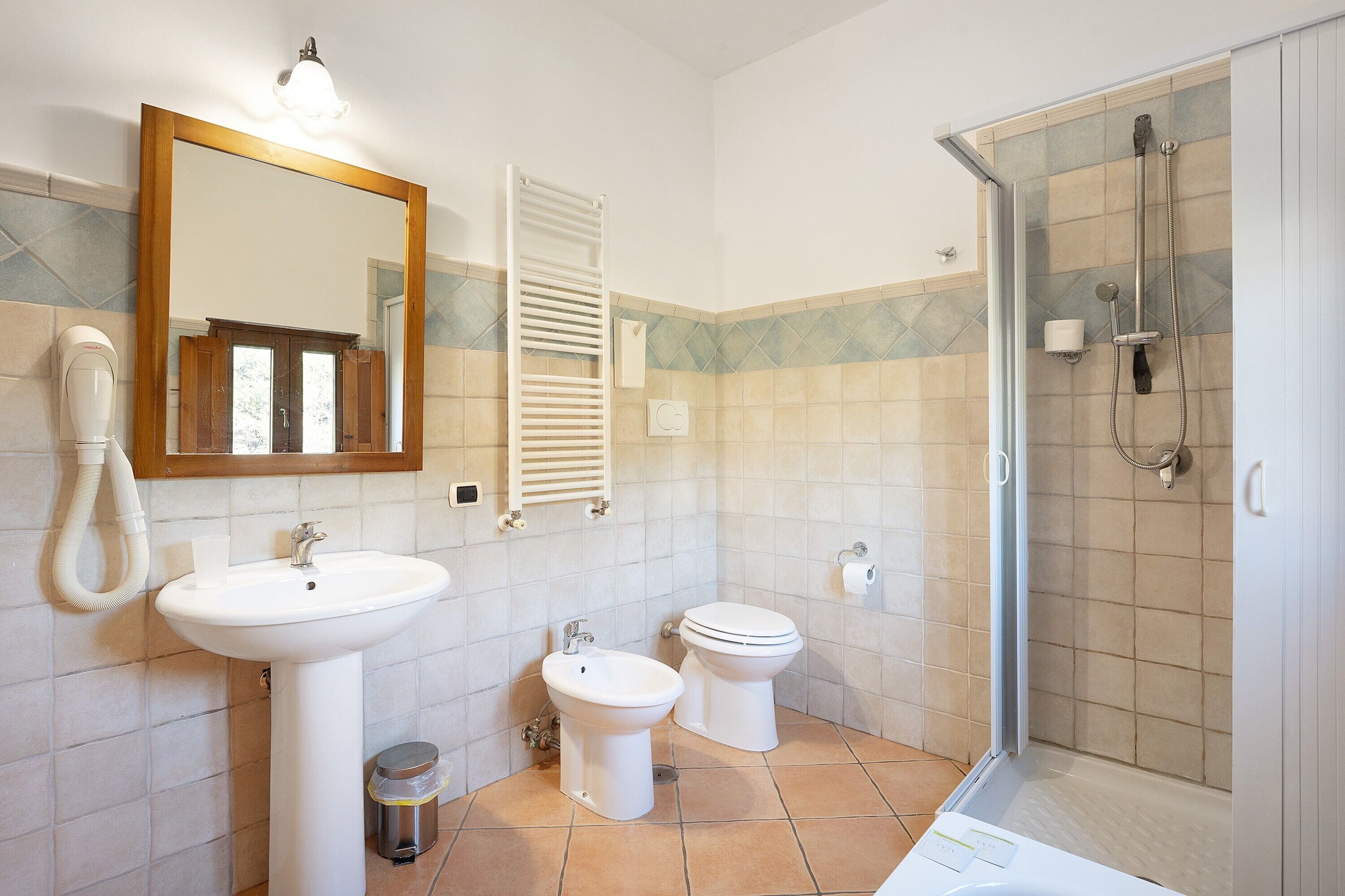 A bathroom with a sink, bidet, toilet, and shower.
