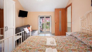 Ein Schlafzimmer mit Bett, einem an der Wand befestigten Fernseher, einer Balkontür und einem Kleiderschrank.