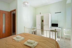 Een slaapkamer met een bed, een kledingkast, een bureau met een computer en een stoel.