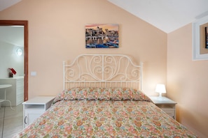 A bedroom with a bed, a nightstand, a bedside table, a wall-mounted picture, and a small desk with a chair. - Apartment 'Bilocale Standard' with Sea View, Shared Garden and Wi-Fi (Gragnano)