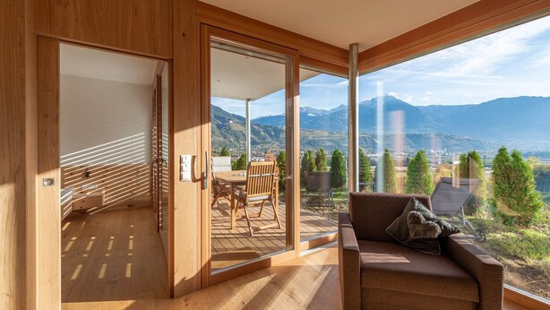 Ein modernes Zimmer mit Holzboden, einer Couch mit Kissen, einem Tisch und Stühlen.
