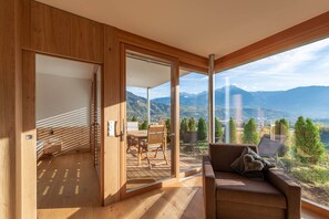 Una camera moderna con pavimento in legno, un divano con cuscini, un tavolo e sedie.