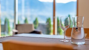 Ein Tisch mit einem klaren Glas und einer Wasserkaraffe, ein Fenster mit Blick auf die Berge.
