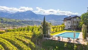 Ein Pool mit Blick auf Berge, ein Haus und Weinreben.