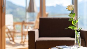 A room with a window, a chair, a table, and a vase with a single white rose. - Chalet 'Moosbichlerhof  Rosalia' with Mountain View, Shared Pool and Wi-Fi (Marling)