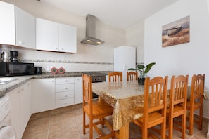 A kitchen with white cabinets, a granite countertop, a stove, and a dining table with chairs.