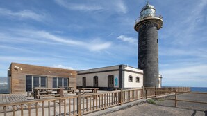 A lighthouse with a wooden deck and a building with arched windows. - Vacation Home 'Buganvilla' with Sea View and Wi-Fi (Pájara)