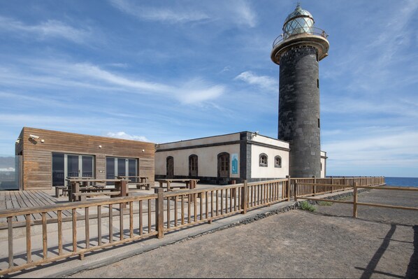 A lighthouse with a wooden deck and a building with arched windows.
