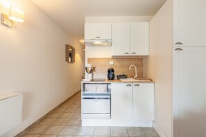 A compact kitchen with white cabinets, a built-in dishwasher, and a coffee maker. - Studio 'Sanary Soleil Et Douceur 3' with Shared Pool, Wi-Fi and Air Conditioning (Sanary-sur-Mer)