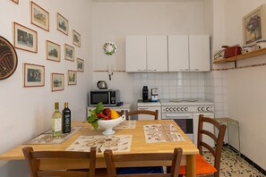 A kitchen with white cabinets, a microwave, a coffee maker, and a dining table with chairs.