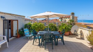 A terrace with a table, chairs, and an umbrella. - Apartment 'Appartamento Vista Mare' with Sea View, Wi-Fi and Air Conditioning (San Vincenzo)
