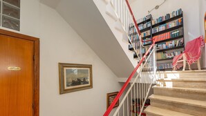 A staircase with red railings, a wooden door, and a bookshelf filled with books. - Apartment 'Appartamento Vista Mare' with Sea View, Wi-Fi and Air Conditioning (San Vincenzo)