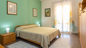 A bedroom with a bed, nightstands, a window with curtains, and framed pictures on the wall. - Apartment 'Appartamento Vista Mare' with Sea View, Wi-Fi and Air Conditioning (San Vincenzo)