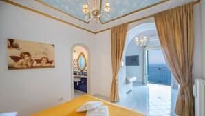 A hotel room with a bed, a bathroom with a mirror, and a view of the outside. - Villa 'Luxury  Soleluna Con Jacuzzi' with Sea View, Wi-Fi and Air Conditioning (Praiano)