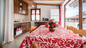 Een keuken met houten kastjes, een eettafel met een rood-witte tafelkleed en een bloevas.