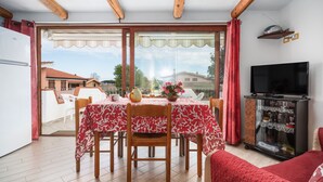 Een eetgedeelte met een tafel voor vier personen, een televisie en een schuifdeur naar een terras.