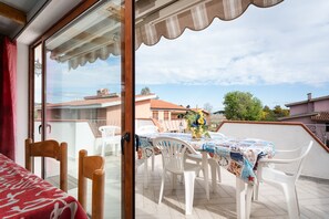 A balcony with a table, chairs, and a view of buildings. - Holiday Home 'Al Mare da Mémé' with Sea View, Private Terrace & Air Conditioning (Budoni)