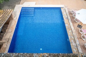 Une piscine rectangulaire avec des marches permettant d’y accéder, entourée d’une bordure en pierre.