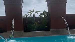A swimming pool with water jets, surrounded by a building with decorative arches and a tiled wall. - Vacation 'Dream Home Beny' with Sea View, Wi-Fi and Air Conditioning (Palm-mar)