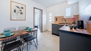 A modern kitchen with a wooden island, black chairs, and a framed artwork on the wall.