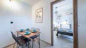 A modern room with a wooden dining table, chairs, a bed, and framed artwork on the walls.