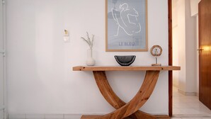 Une console en bois ornée d’un bol et d’un vase, d’une œuvre d’art encadrée et d’un petit objet décoratif accroché au mur.