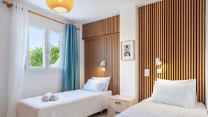 Une chambre d’hôtel avec deux lits, une fenêtre avec des rideaux, une table de chevet avec une lampe et un mur avec des lambris en bois verticaux.